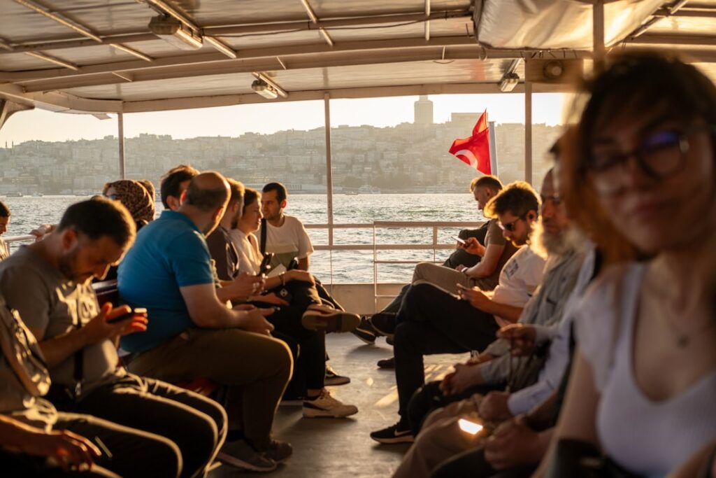 Passagiere auf einem Boot mit Blick auf die Küste und eine türkische Flagge im Hintergrund.