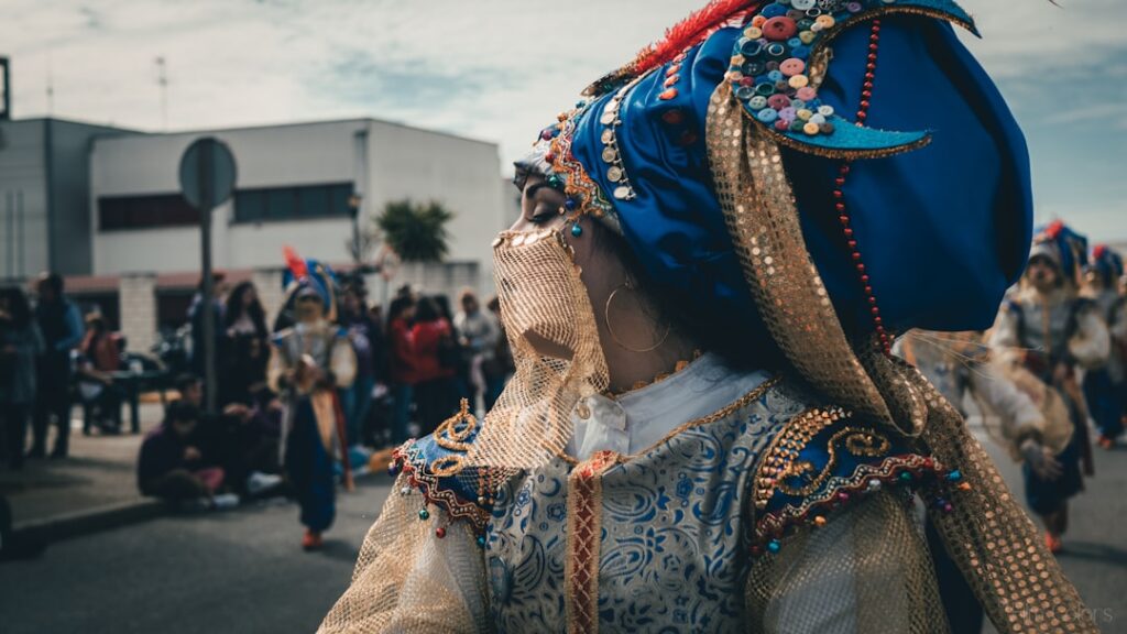 Frau in traditioneller Tracht mit buntem Kopfschmuck und goldenen Verzierungen während eines Festumzugs.