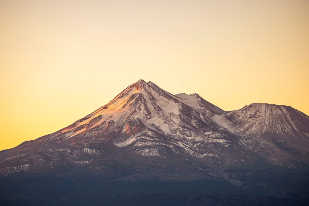 Schneebedeckter Berg mit Sonnenuntergangslicht, das die Gipfel beleuchtet.