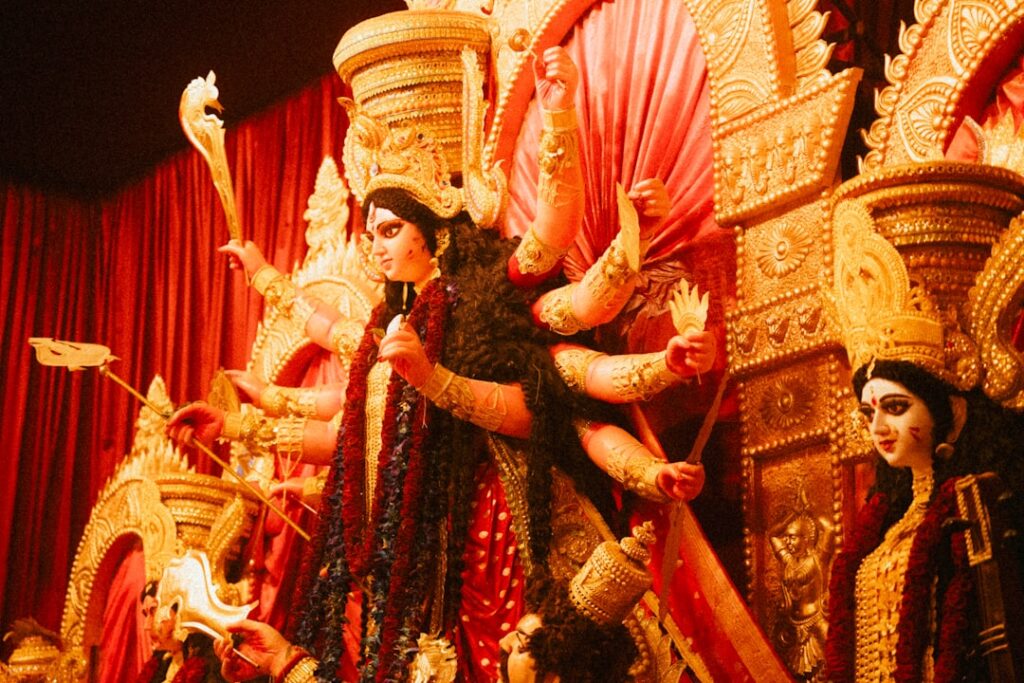 Hindu-Göttin Durga mit mehreren Armen, geschmückt mit Blumen und goldenen Ornamenten in einem festlichen Rahmen.