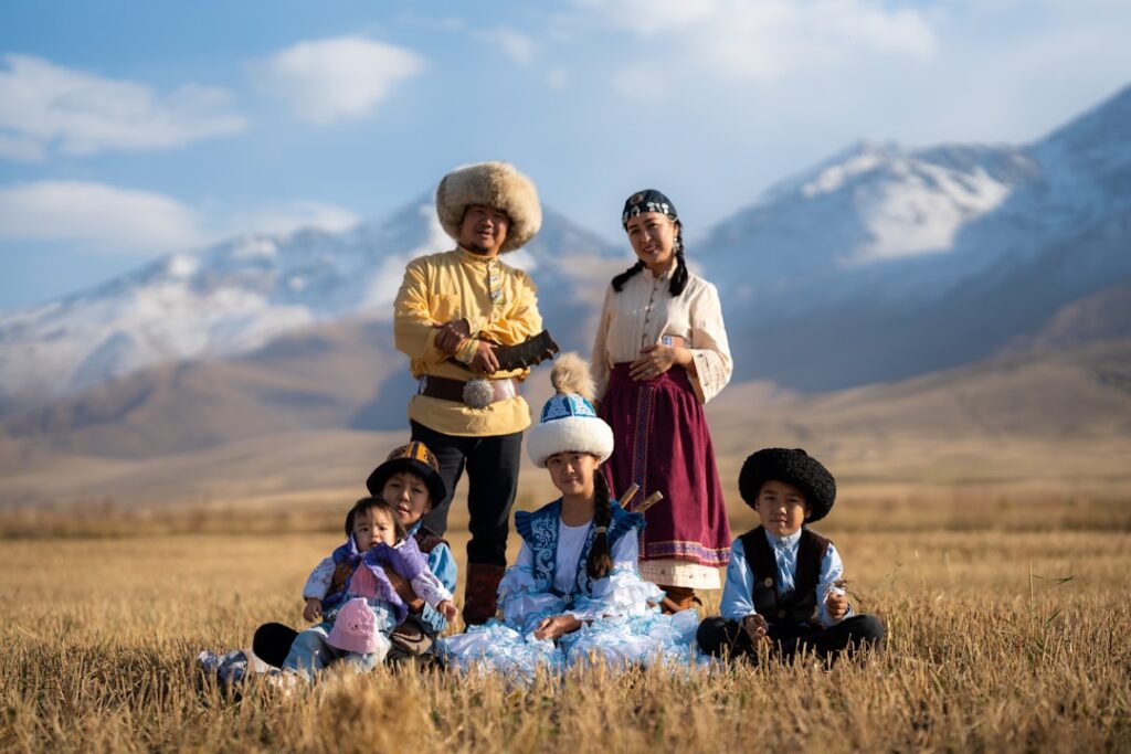 Familie in traditioneller Kleidung posiert auf einem Feld mit Bergen im Hintergrund.