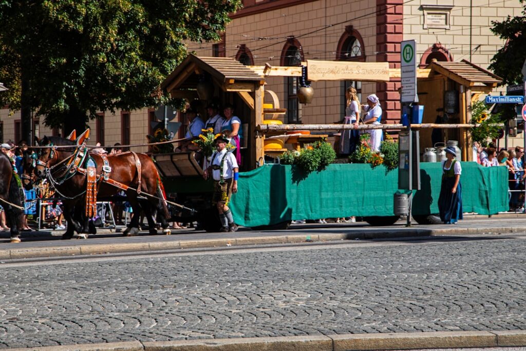 Pferdegezogene Wagen mit Holzaufbau und Personen in traditioneller Kleidung während einer Veranstaltung.