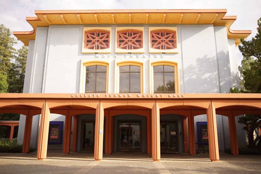 Haupteingang des Main Theatre mit orangefarbenem Vordach und bunten Fenstern.