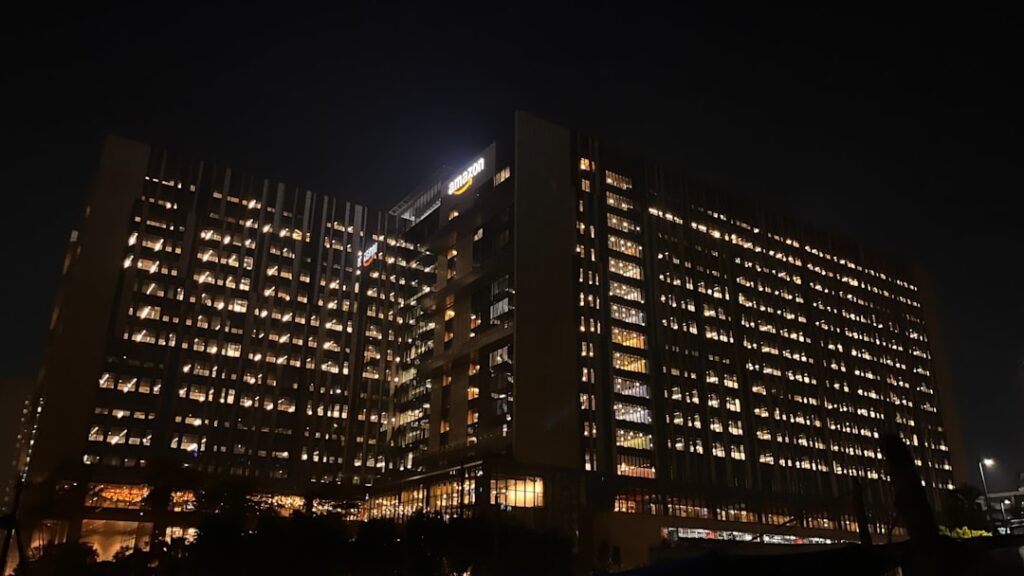 Moderne Bürogebäude mit beleuchteten Fenstern bei Nacht, das eine geschäftige Atmosphäre vermittelt.