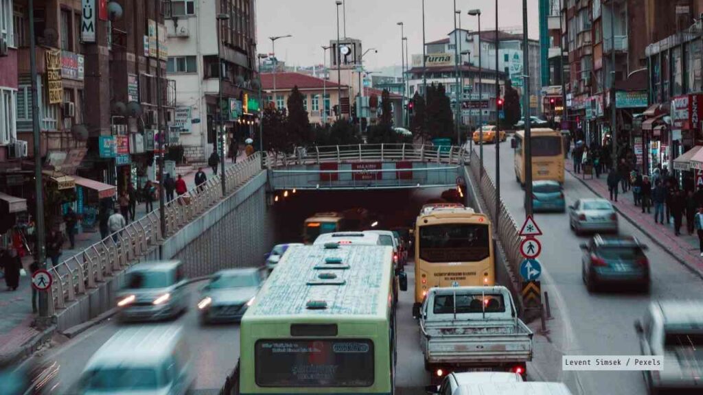 Verkehrsszene mit Autos und Bussen auf einer Stadtstraße, die zu einem Tunnel führt.