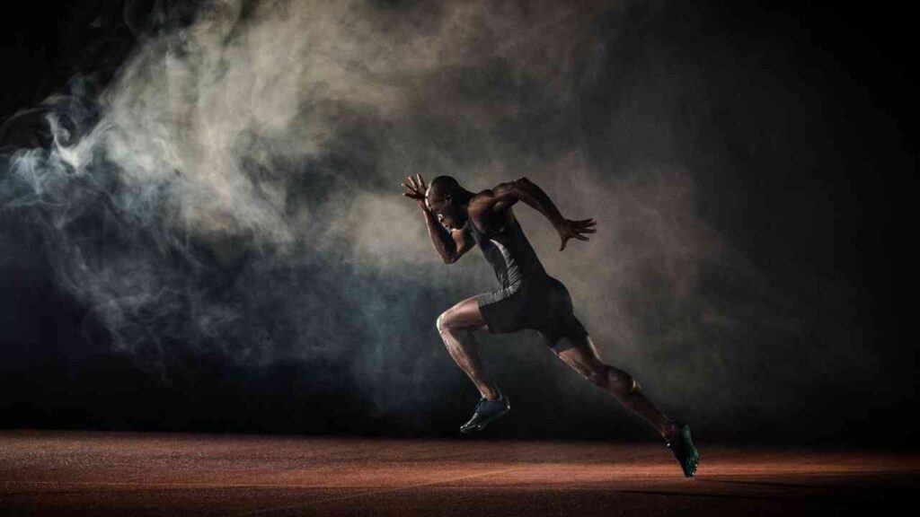Athlet in Sportkleidung sprintet auf einer Laufbahn, umgeben von Rauch und Schatten.