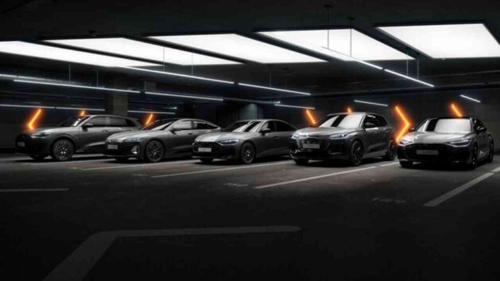 Sechs Audi-Modelle in verschiedenen Grautönen in einer modernen Parkgarage aufgereiht.