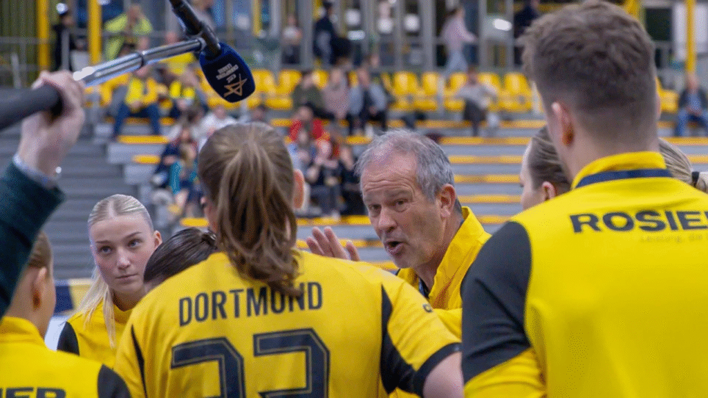 Trainer spricht mit den Spielerinnen der BVB-Frauenmannschaft während einer Besprechung vor einem Spiel.