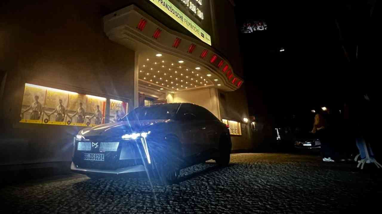 Schwarzes Auto mit markanten Scheinwerfern, das vor einem beleuchteten Gebäude steht.