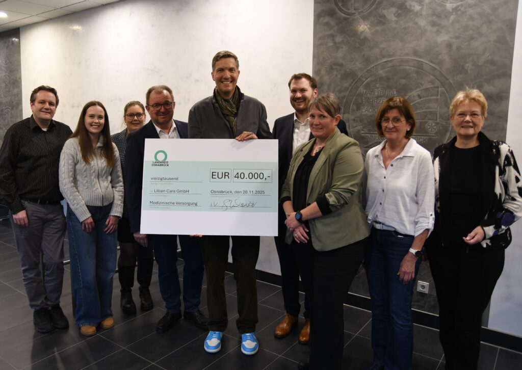 Gruppenfoto mit einem großen Scheck über 40.000 Euro, präsentiert von einer Person und umgeben von weiteren Personen.