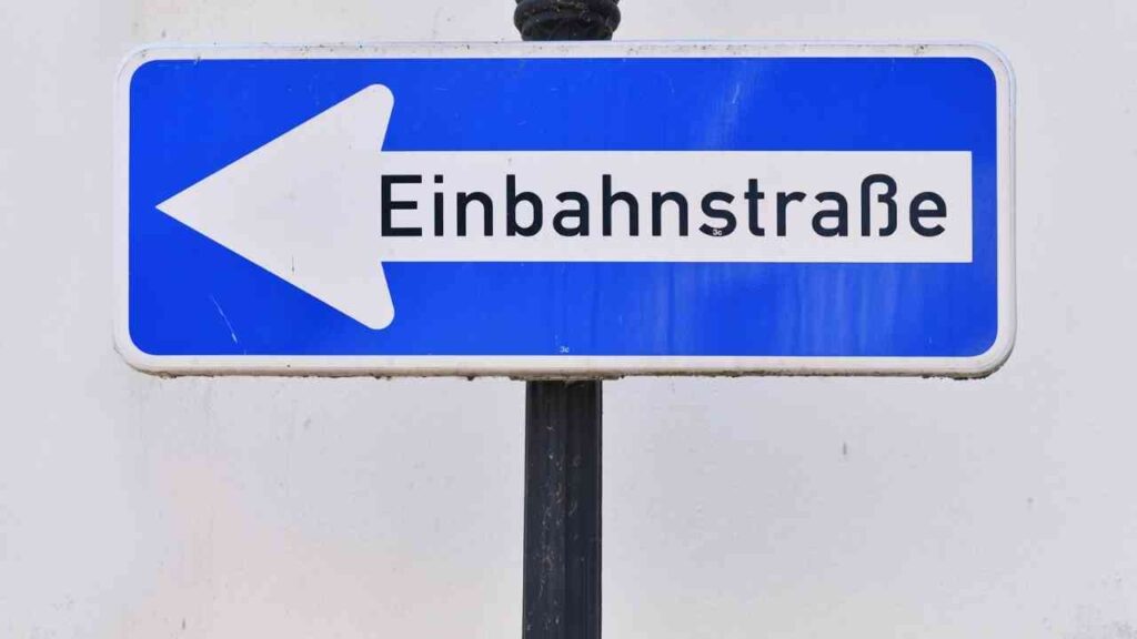 Verkehrsschild mit blauer Hintergrundfarbe, das auf eine Einbahnstraße hinweist.