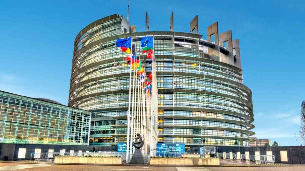 Das Europäische Parlament in Straßburg mit Flaggen der Mitgliedstaaten und moderner Architektur.