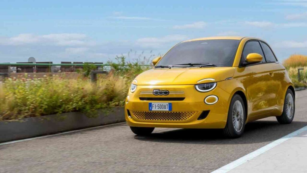 Gelber Fiat 500 Hybrid fährt auf einer Straße mit klarer Sicht und modernem Design.