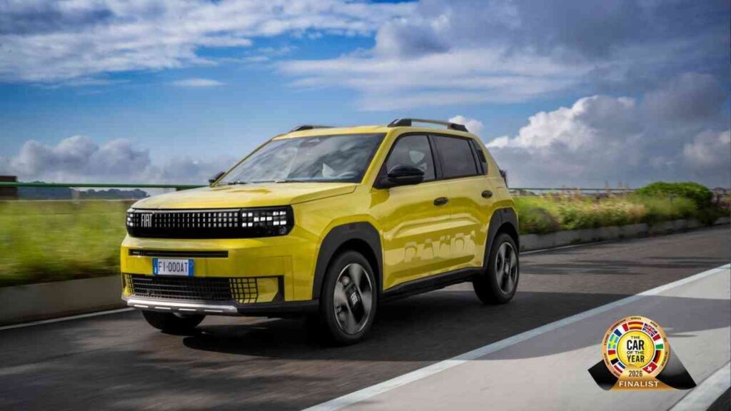 Gelber Fiat Grande Panda, ein kompakter SUV, fährt auf einer Straße mit blauen Himmel im Hintergrund.