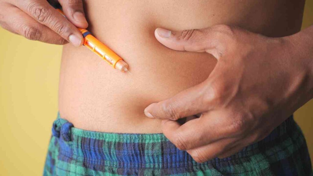 Person injiziert Insulin mit einem Pen in den Bauchbereich, um Diabetes zu behandeln.