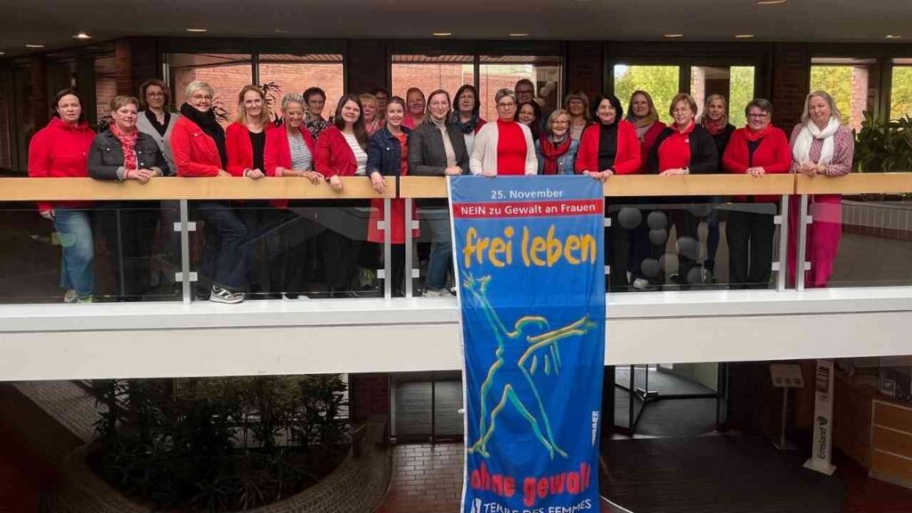 Gruppierung von Frauen in roten Kleidungsstücken, die ein Banner gegen Gewalt an Frauen halten.