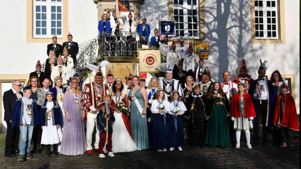 Karnevalsprinzenpaar und Mitglieder der Karnevalsgesellschaft posieren vor einem historischen Gebäude in Rheine.