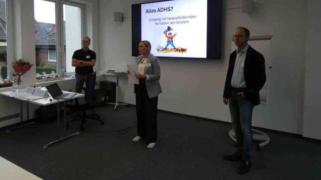 Drei Personen in einem Seminarraum während einer Präsentation über ADHS und den Umgang mit Kindern.