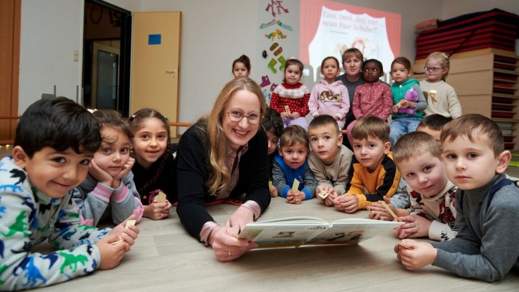 Eine Erzieherin liest Kindern in einer Kita in Dissen ein Buch vor, während die Kinder um sie herum sitzen.
