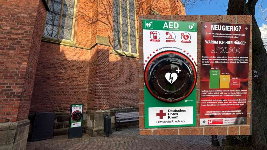 Defibrillator an einer Wand mit Informationen zur Nutzung und einem Hinweis des Deutschen Roten Kreuzes.