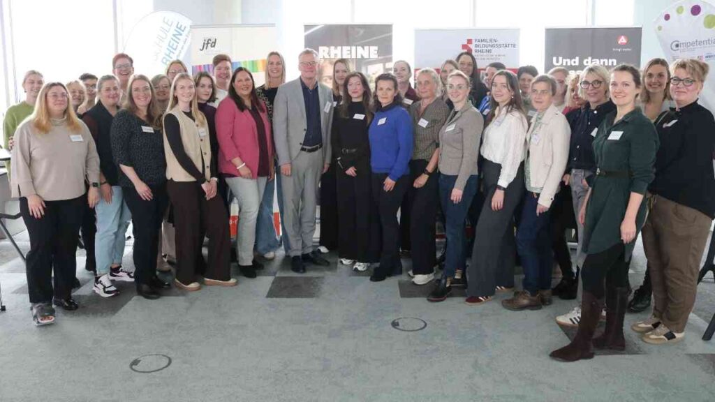 Gruppe von Frauen und Männern, die an einer Mentoring-Veranstaltung teilnehmen, stehen zusammen in einem Raum.
