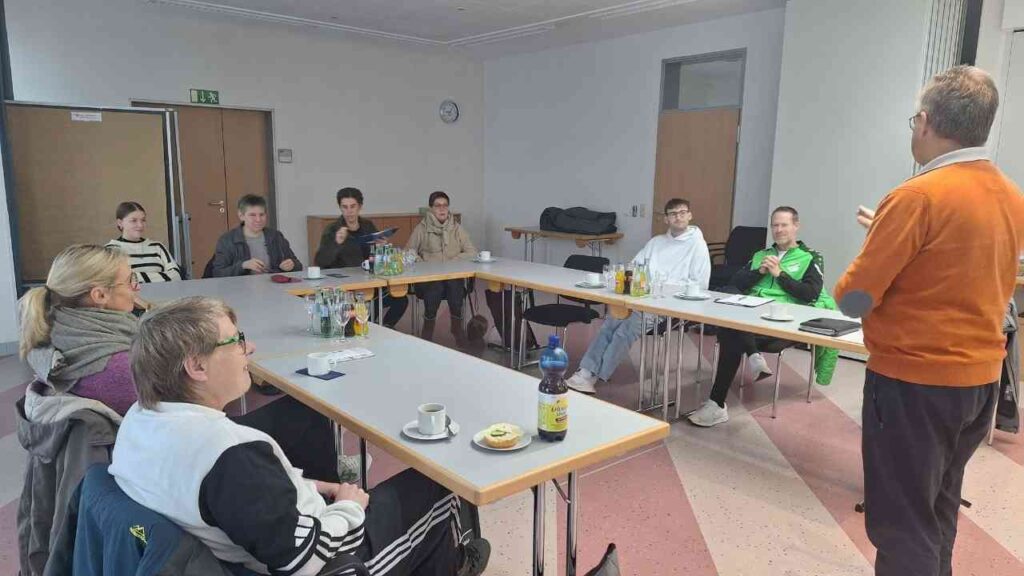 Gruppe von Teilnehmern in einem Schulungsraum, die einem Dozenten während einer Fortbildung zuhören.