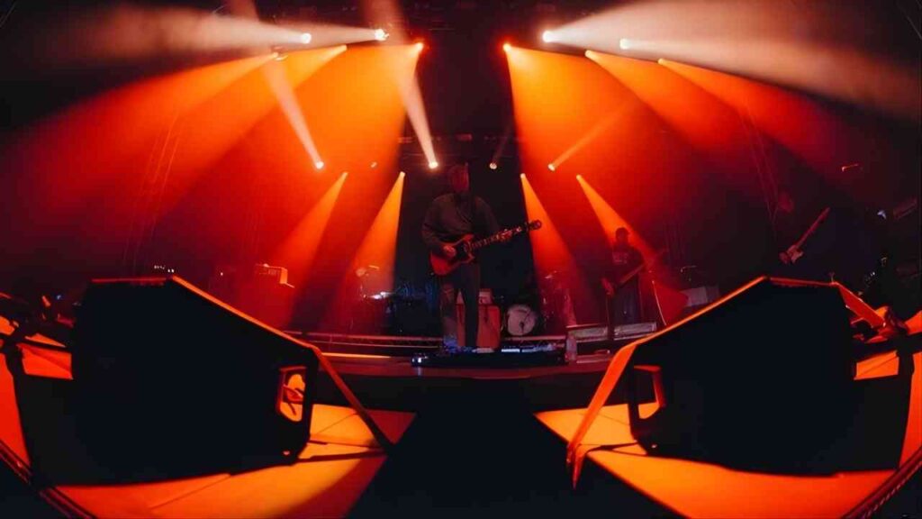 Musiker auf der Bühne mit Gitarre, umgeben von orangefarbenem Licht und Scheinwerfern während eines Konzerts.