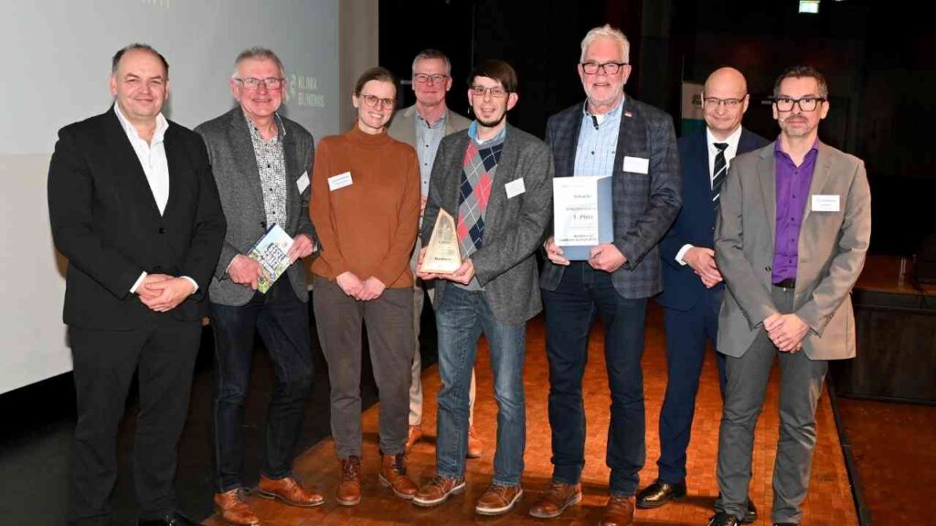 Gruppe von Personen, die bei einer Veranstaltung auf einer Bühne stehen und Auszeichnungen halten.