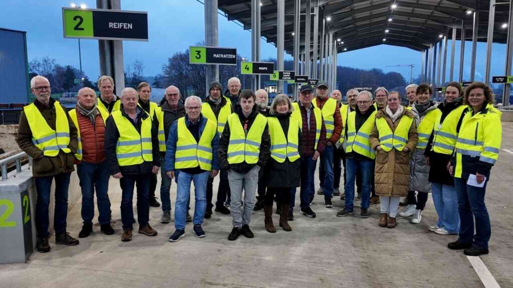 Gruppe von Menschen in gelben Warnwesten, die sich an einem Veranstaltungsort versammeln.