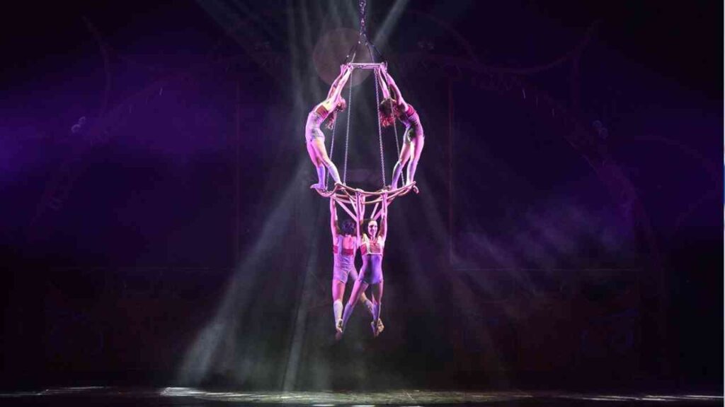 Vier Akrobaten führen eine Luftakrobatik-Nummer an einem trapezähnlichen Gerät in einer Zirkusaufführung durch.