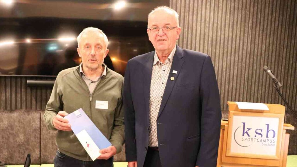 Zwei Männer stehen nebeneinander im Sportcampus Emsland, einer hält ein Dokument in der Hand.