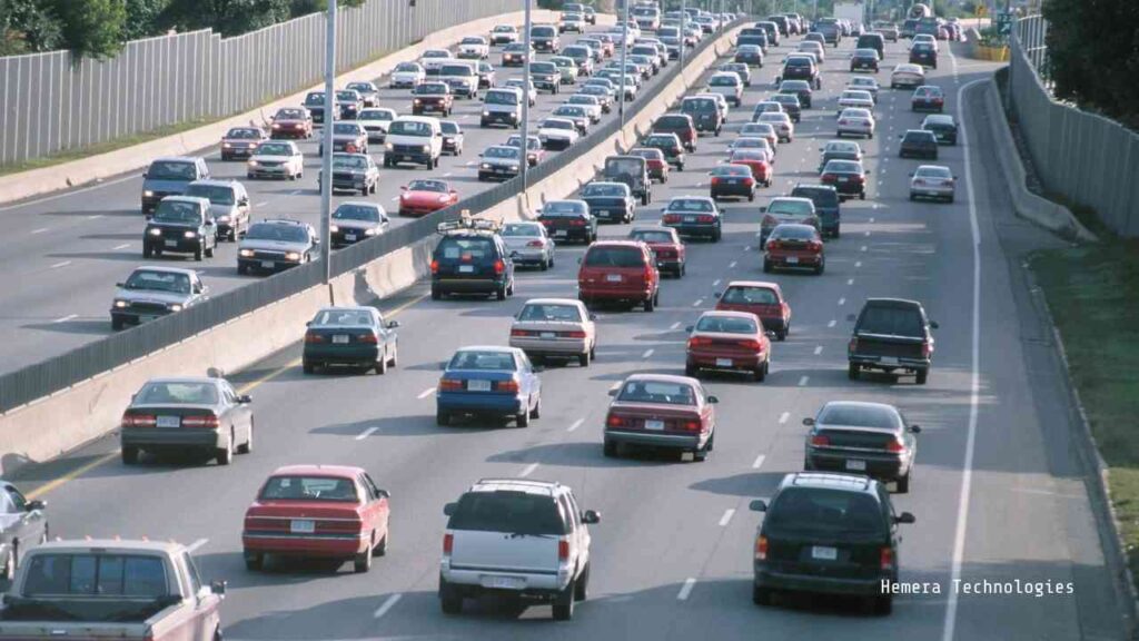 Verkehr auf einer mehrspurigen Straße mit zahlreichen Fahrzeugen in beiden Fahrtrichtungen.