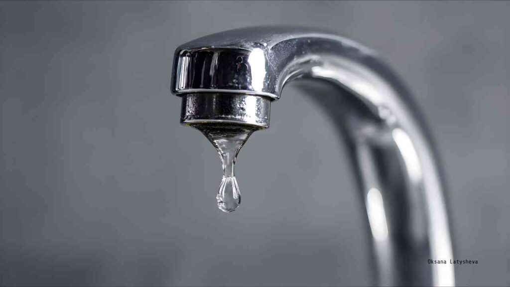 Ein glänzender Wasserhahn mit einem einzelnen Wassertropfen, der herabfällt.