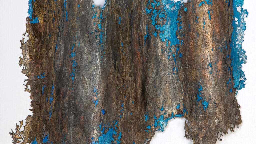 Abstrakte Wandkunst aus Metall mit blauen und bronzefarbenen Elementen, die eine organische Form bildet.