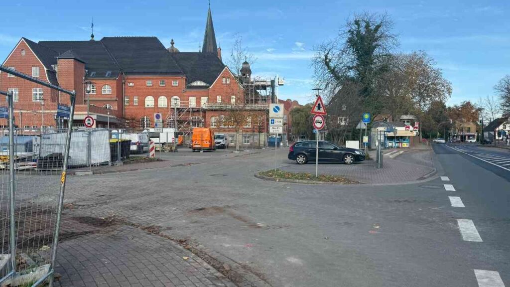 Blick auf eine Straßenkreuzung mit Baustellen und einem orangefarbenen Lieferwagen in der Nähe eines historischen Gebäudes.