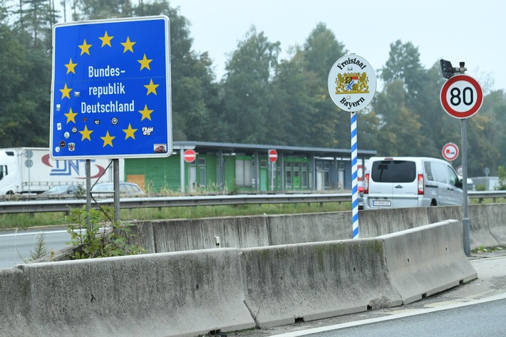 Verkehrsschild mit dem Hinweis auf die Bundesrepublik Deutschland und das Bundesland Bayern an einer Straße.