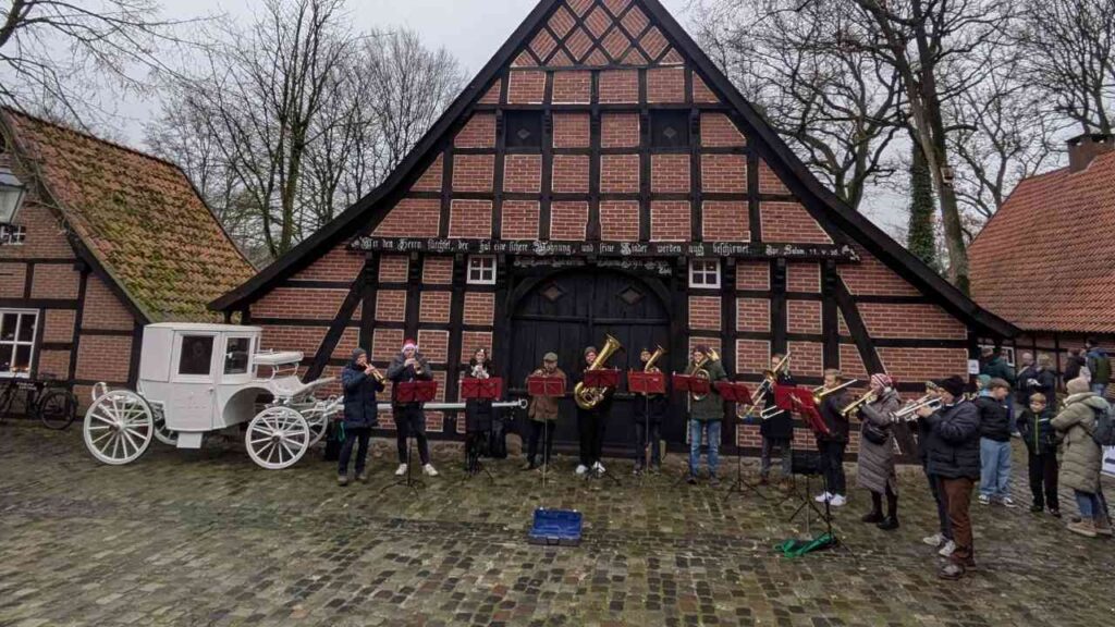 Musikgruppe mit Blasinstrumenten vor einem historischen Fachwerkhaus in Haselünne.