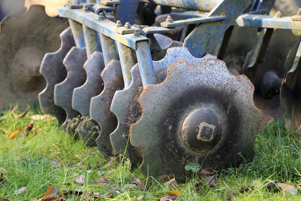 Agrarische Scheiben eines Pfluges mit gezackten Kanten, die auf grünem Gras stehen.