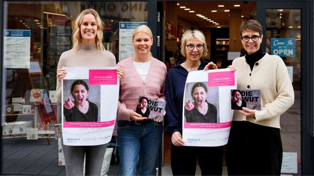Vier Frauen halten Plakate mit dem Schriftzug 'Die Wut' und einem Bild einer schreienden Frau in einem Schaufenster.