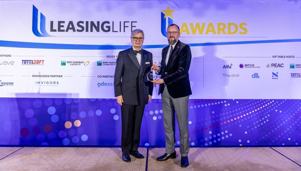 Zwei Männer stehen auf einer Bühne und halten einen Preis bei den Leasing Life Awards.