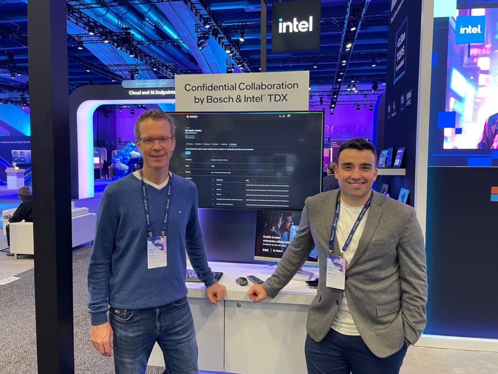 Zwei Männer stehen vor einem Bildschirm mit Informationen zur Zusammenarbeit zwischen Bosch und Intel TDX auf einer Messe.
