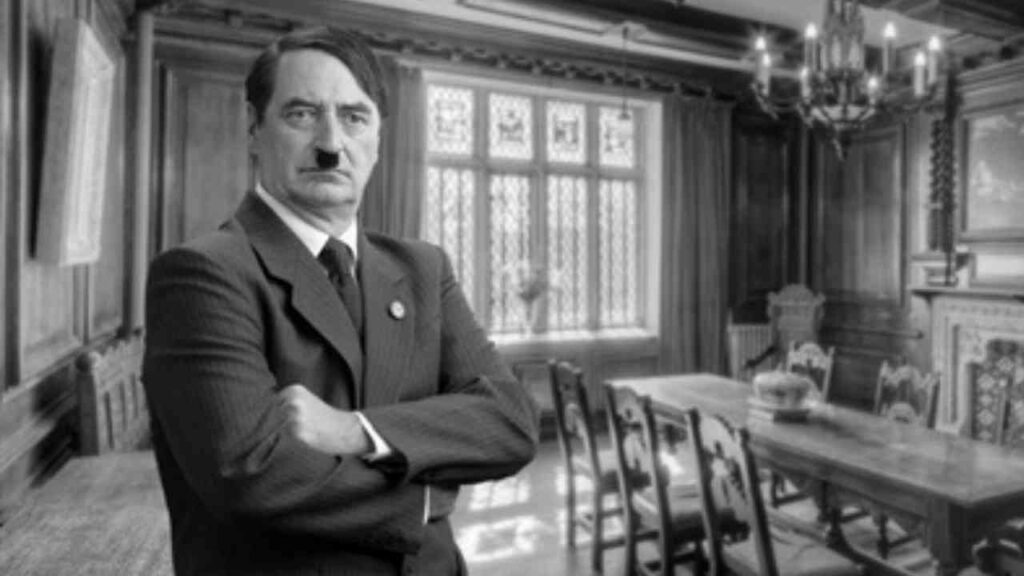 Schwarz-weißes Porträt von Adolf Hitler in einem historischen Raum mit einem langen Tisch und Stühlen.