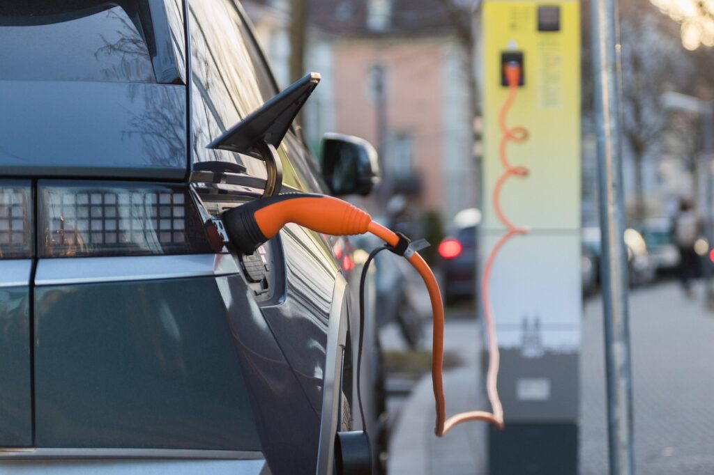 Elektroauto mit orangefarbenem Ladekabel, das an einer Ladestation angeschlossen ist.