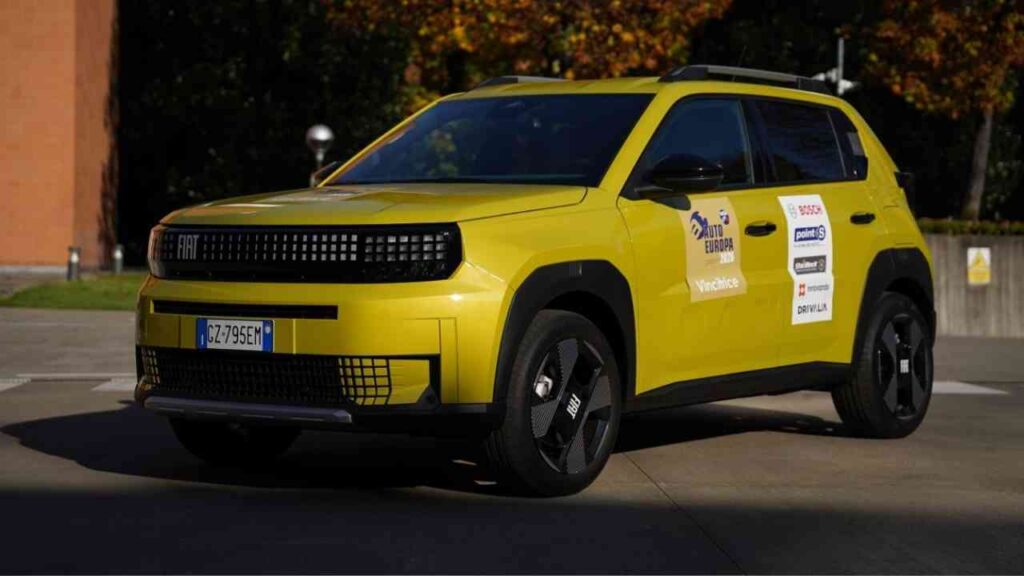 Gelbes Auto der Marke Fiat, Modell Grande Panda, mit verschiedenen Logos auf der Karosserie, aufgenommen im Freien.