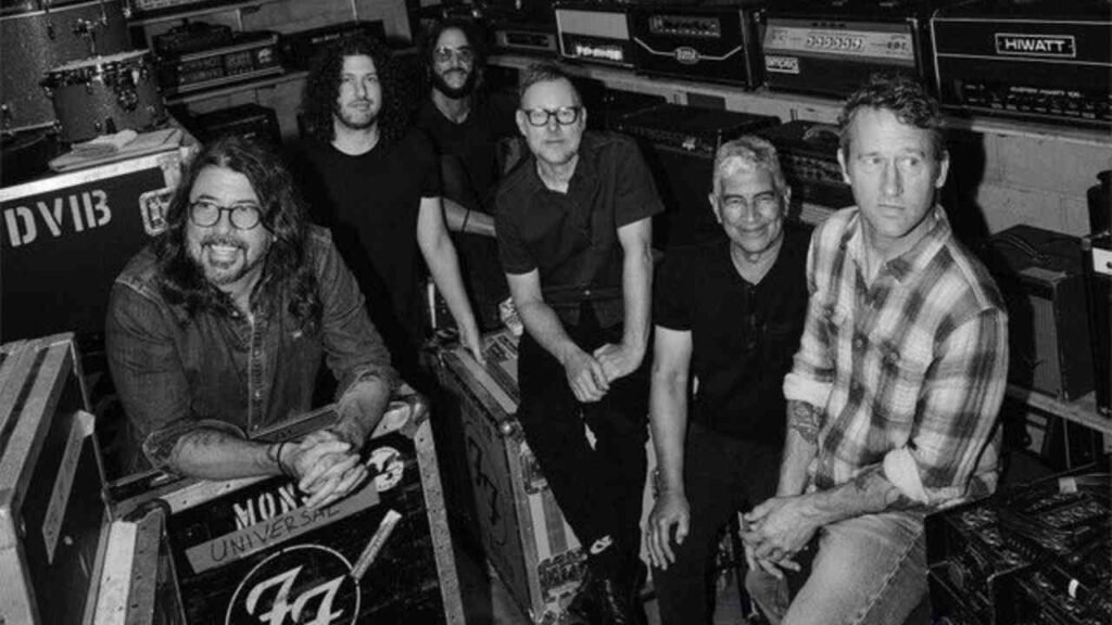 Bandmitglieder der Foo Fighters posieren in einem Proberaum mit Verstärkern und Equipment.