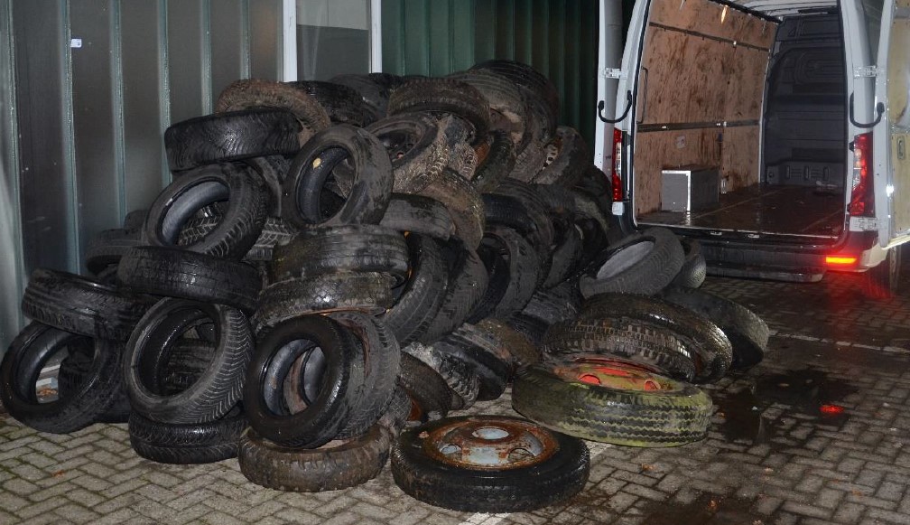 Haufen von alten Reifen, die in einem Transporter und auf dem Boden gestapelt sind.