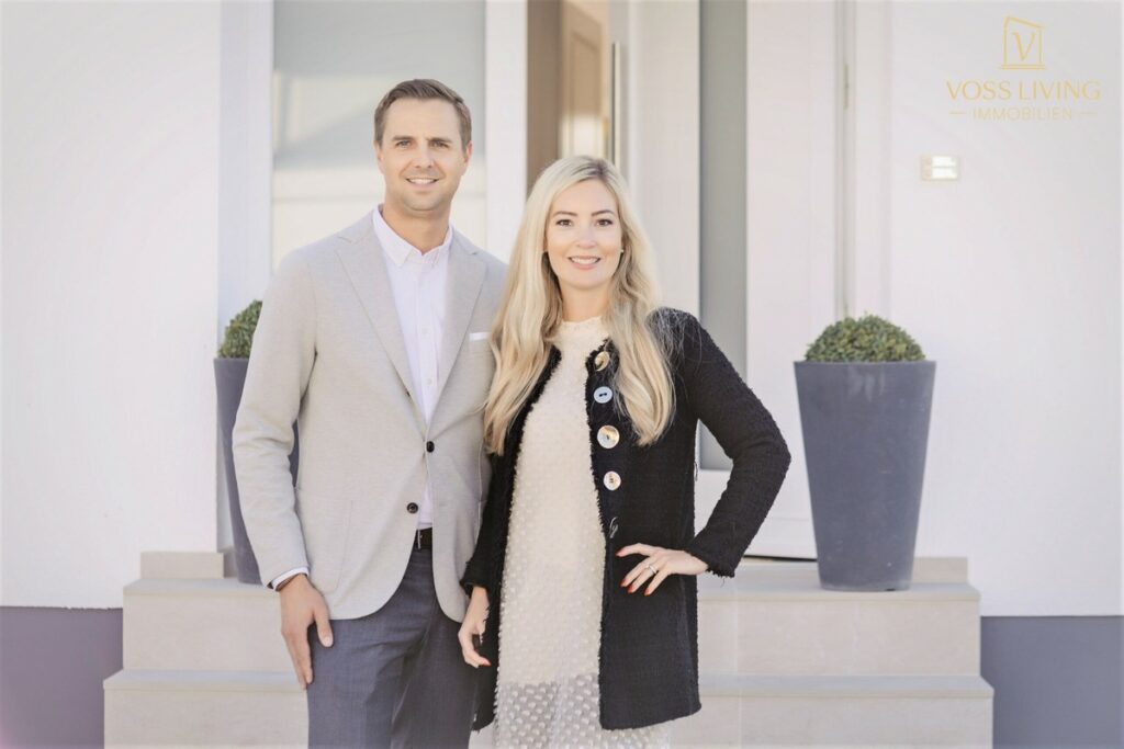 Paar steht vor einem modernen Gebäude mit neutralen Farben und minimalistischer Architektur.