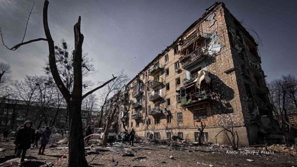Zerstörtes Wohngebäude mit beschädigten Balkonen und zerbrochenen Fenstern in einem urbanen Gebiet.
