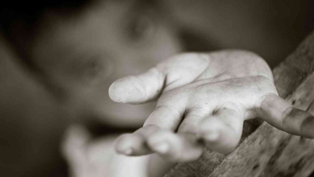 Nahaufnahme einer ausgestreckten Hand eines Kindes, die um Hilfe bittet, in Schwarz-Weiß gehalten.
