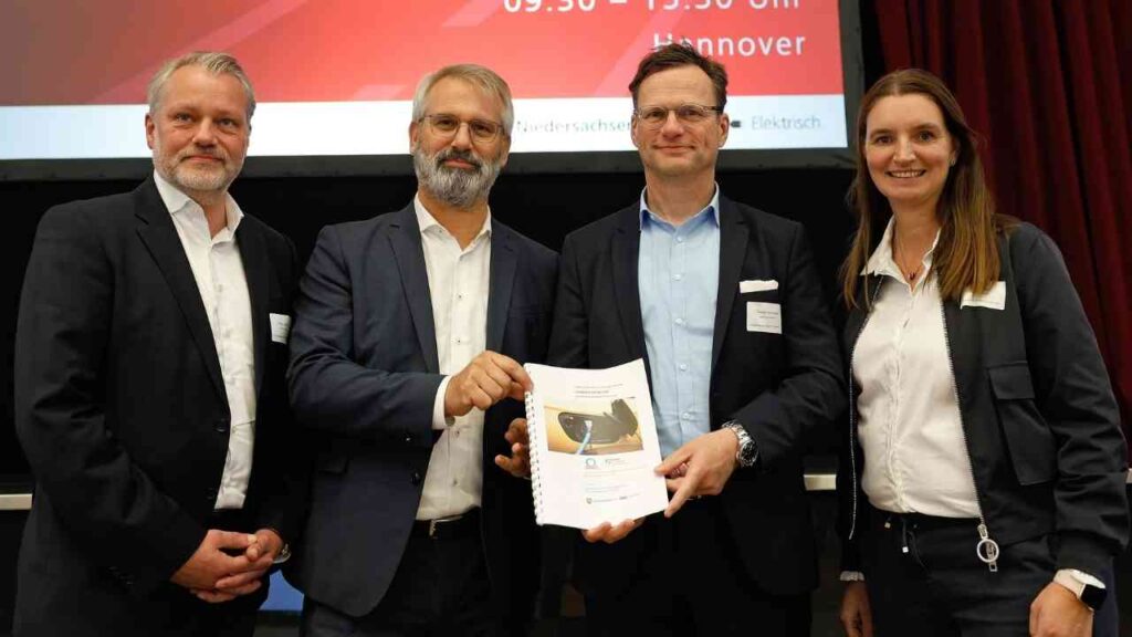 Vier Personen stehen zusammen und halten ein Dokument bei einer Veranstaltung in Hannover.